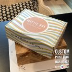 Yellow striped custom printed box for Mattie Rae featuring a coral circular logo and clean brand design.