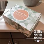 Custom printed box with coral and green branding for Mattie Rae, displayed on a white desk